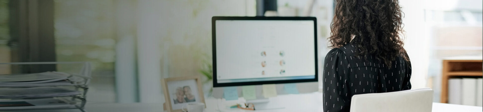 Woman with back to camera looking at computer.