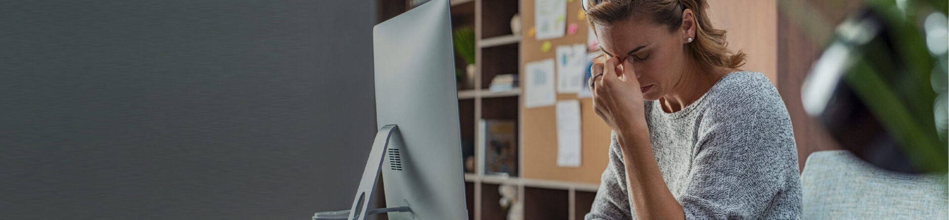 Woman sitting at computer with head in hands.